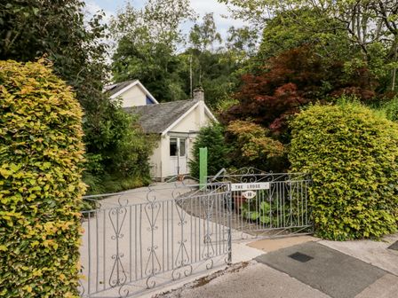 A gated driveway with a house behind surrounded by trees and bushes at The Lodge in Ambleside
