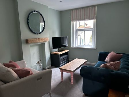 A living room with sofas a coffee table a television on a stand and a window at Secret Garden 34C Clarence Street Dartmouth