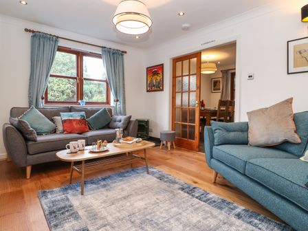 A living room with two sofas a coffee table and blue curtains at Cherry Tree Cottage in Windermere