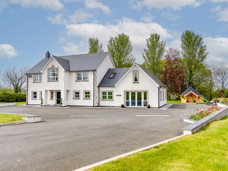 A large white house with multiple windows and a paved driveway surrounded by grass and trees at Parc Y Deri in Rhos-y-garth near Aberystwyth