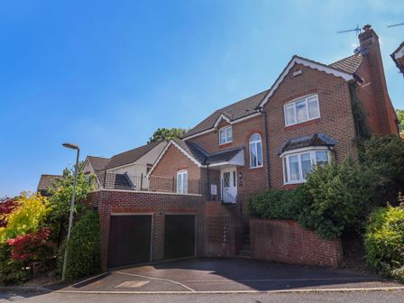 A brick house with a double garage and front steps surrounded by greenery at Lyme Bay View in Lyme Regis