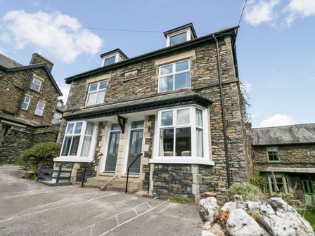A stone house with two front doors and bay windows with parking spaces in front at Park Beck in Windermere