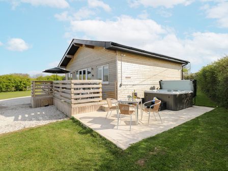 An outdoor patio with a hot tub and seating area at Heritage Retreat Monknash