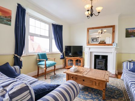 A living room with striped sofas wooden coffee table fireplace and television at The Pink House in Felixstowe Suffolk