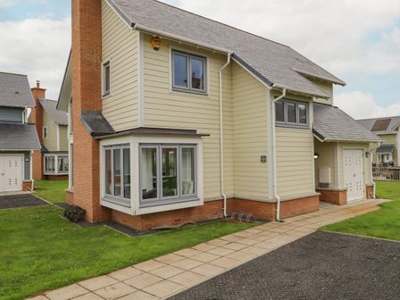 A two-story detached house with cream siding and brick chimney at Turning Tide in Beadnell