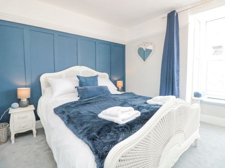 A bedroom with a white bed blue pillows blue throw and a blue accent wall at 8 Above Town in Dartmouth