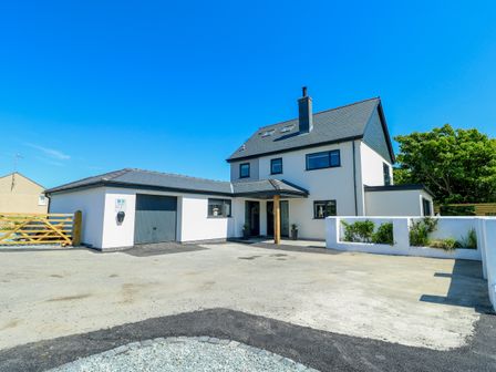 A house with a garage and driveway at Iscoed in Rhosneigr