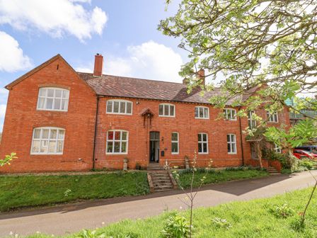 A two story brick house with multiple white framed windows and a small set of stairs at the entrance at Red House in Lyme Regis