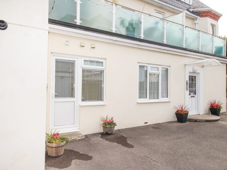 An exterior view of a building with a door and windows and flower pots at the entrance at Sandy Haven in Swanage