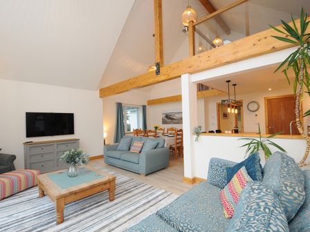 A living room with sofas a coffee table a television and a dining area at Gwennel Neyth in Mitchell