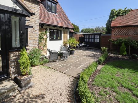 A patio area with wicker chairs and a table outside a stone and white building at Woodbine Cottage in Cleeve Prior near Bidford-On-Avon