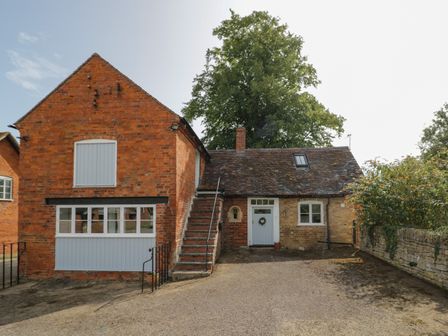 A brick house with an external staircase and a blue door at Chapel Cottage in Netherton near Pershore
