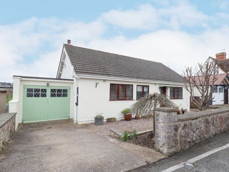 A single story house with a green garage door and a driveway at The Crib in Penrhyn Bay