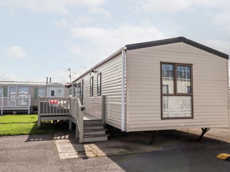 A mobile home with steps and a private parking sign at Beachcomber D35 in Towyn