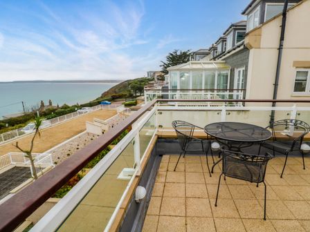 A balcony with a round metal table and four metal chairs overlooking the sea at Sea View in Carbis Bay