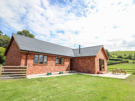 A brick house with multiple windows and a grassy lawn at Awel y Bryn in Rhayader