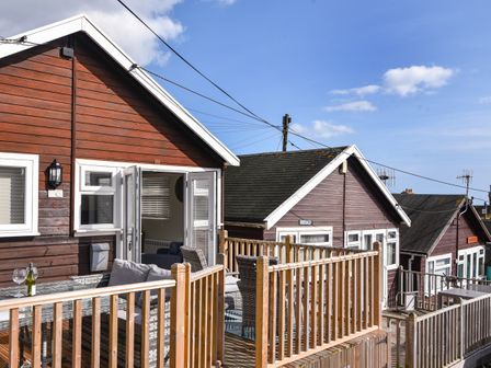 A wooden deck with outdoor furniture and glass door leading inside at Marnie's Rest in Lyme Regis