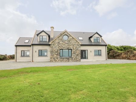 A two story house with stone and beige exterior walls and a grass lawn at Old Field House Slade near Fethard-On-Sea County Wexford