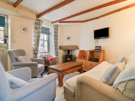 A living room with armchairs sofa wooden coffee table and TV at Aunt Dora's in Port Isaac