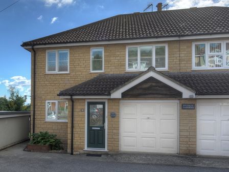 Front exterior of a semi detached house with garage and green door at 2 Studley Gardens Lyme Regis