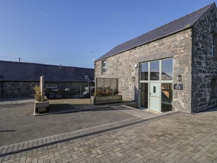 A stone building with glass door and outdoor seating area at The Barn by Lyons in Talybont near Barmouth