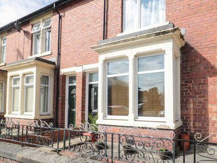 A brick terraced house with bay windows and metal railings at 18 Acklington Road in Amble