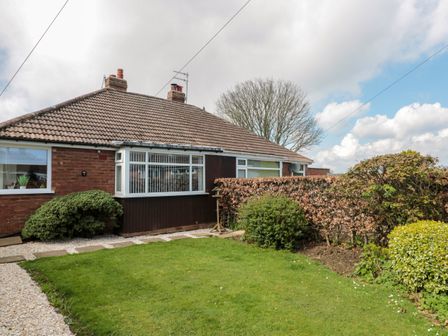 The exterior of a single-story house with a tiled roof surrounded by a garden with grass shrubs and a gravel path at Seaside Cottage in Scarborough