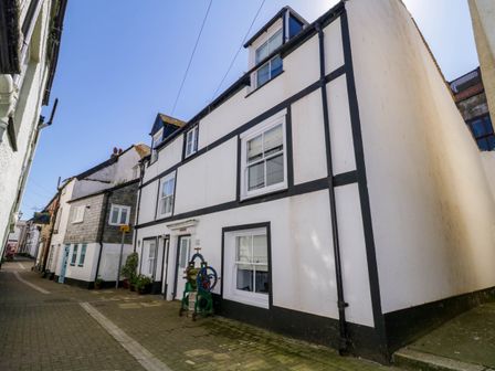 A street view of white buildings with black trim and windows at Sun Cottage in Looe