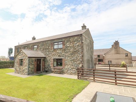 A stone house with a small porch and green lawn at Yr Hen Stabl in Llanwnda near Bontnewydd Gwynedd