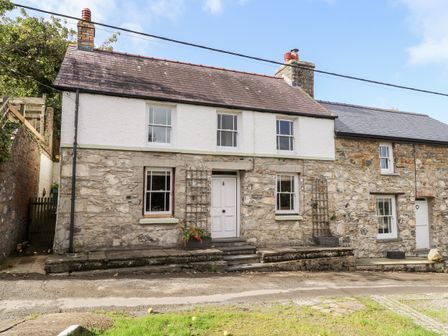 The front exterior of a stone and white plaster house with four windows and a central door at Gartavon in Newport Pembrokeshire