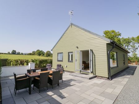 An outdoor patio with a table and chairs next to a green house with open doors at Southend in Welland