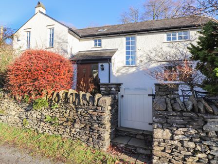 A white stone house with a small front garden behind a stone wall and a white gate at Deer Leap in Satterthwaite near Hawkshead