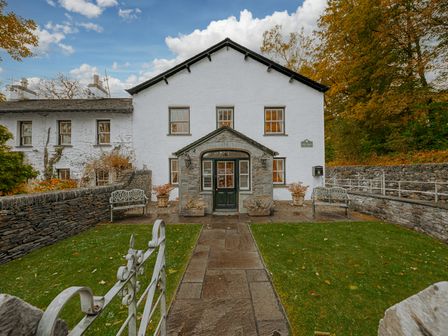 A front view of a white house with a stone pathway and lawn at Gate House Coniston