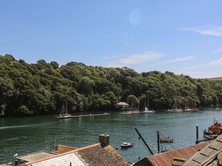 A river with several boats docked near a forested area adjacent to rooftops at 21 Passage Street formerly Panacea in Fowey
