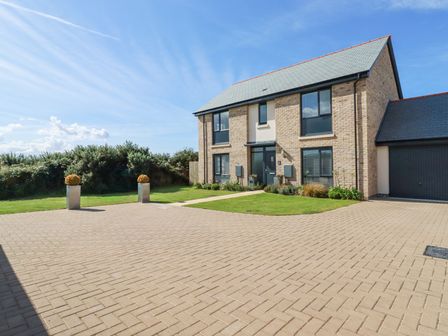 A modern two story house with a paved driveway and grass lawn at Cobalt in St Eval near Mawgan Porth