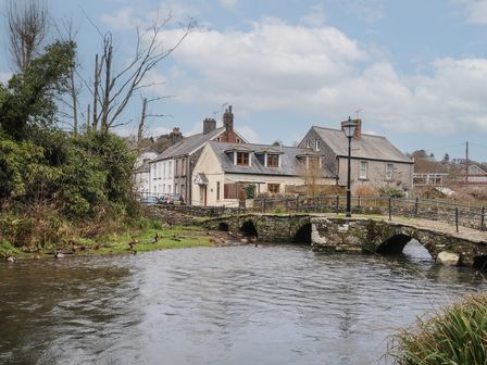 A stone bridge over a river near residential houses and trees at Rainbows End in Launceston