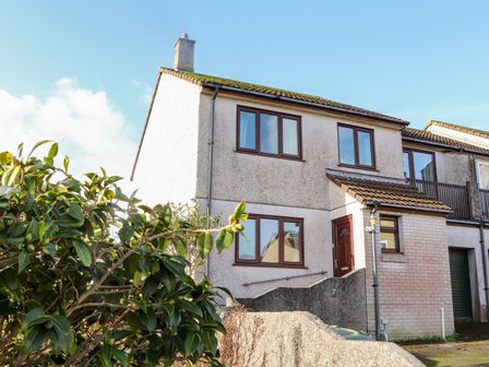 A two-story semi detached house with windows a front door and greenery at Chi an Vre in Newlyn
