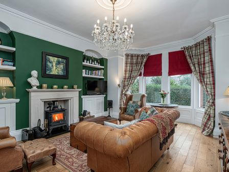 A living room with a fireplace leather sofas and a chandelier at No 22 in Llandudno