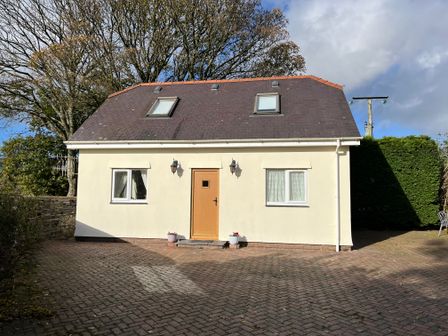 A small house with a brown door and two windows on the ground floor and two roof windows at Country View in Talysarn near Penygroes