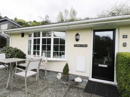 A patio area with a table and chairs outside a house with a black door and a window at T Whit T Woo in Windermere