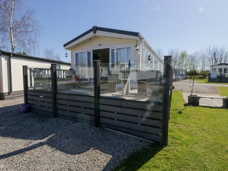 A static caravan with glass and wooden fencing on gravel and grass at Lakeside Haven in Carnforth