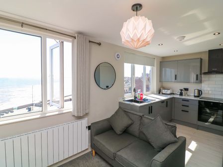 A living room with a sofa and kitchen unit at Apt 9 @ Hunter's Quay in Bridlington