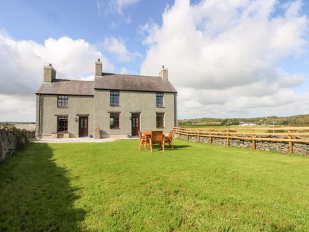 A house with a table and chairs in the garden at Trefor Ganol Beaumaris