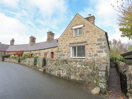 A row of stone cottages with chimneys along a paved street at 5 The Crescent in Caernarfon