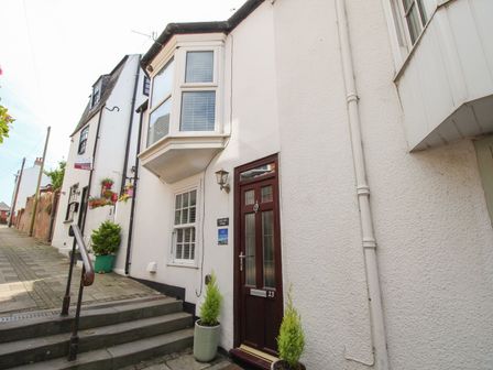 A street view showing the entrance door of Little Gull Cottage with steps and potted plants in Weymouth