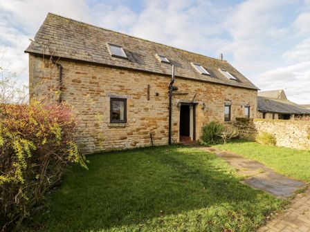 A stone cottage with a slate roof and skylights with a grassy yard and a stone pathway at Well Cottage in Moreton-In-Marsh
