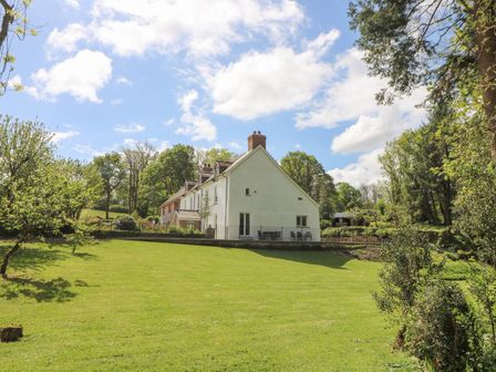 A house with a sloped lawn and trees in a rural setting at Glanduad Fawr in Newport Pembrokeshire
