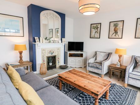 A living room with a wooden coffee table a fireplace a tv and two armchairs at Salvatore in Salcombe