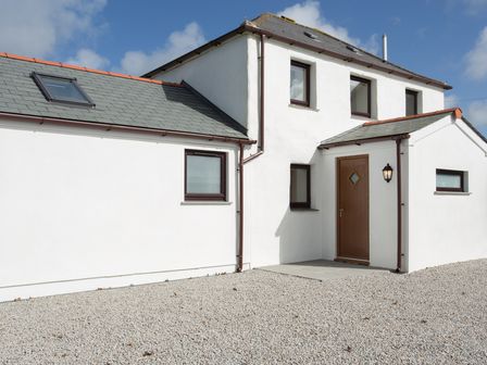 The exterior of a white two-story house with multiple windows a wooden door and a gravel driveway at Cornish Views in Camborne