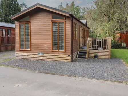 A wooden cabin with large windows and a small staircase leading to a deck at Snuggledown in Troutbeck 5 White Cross Bay near Windermere